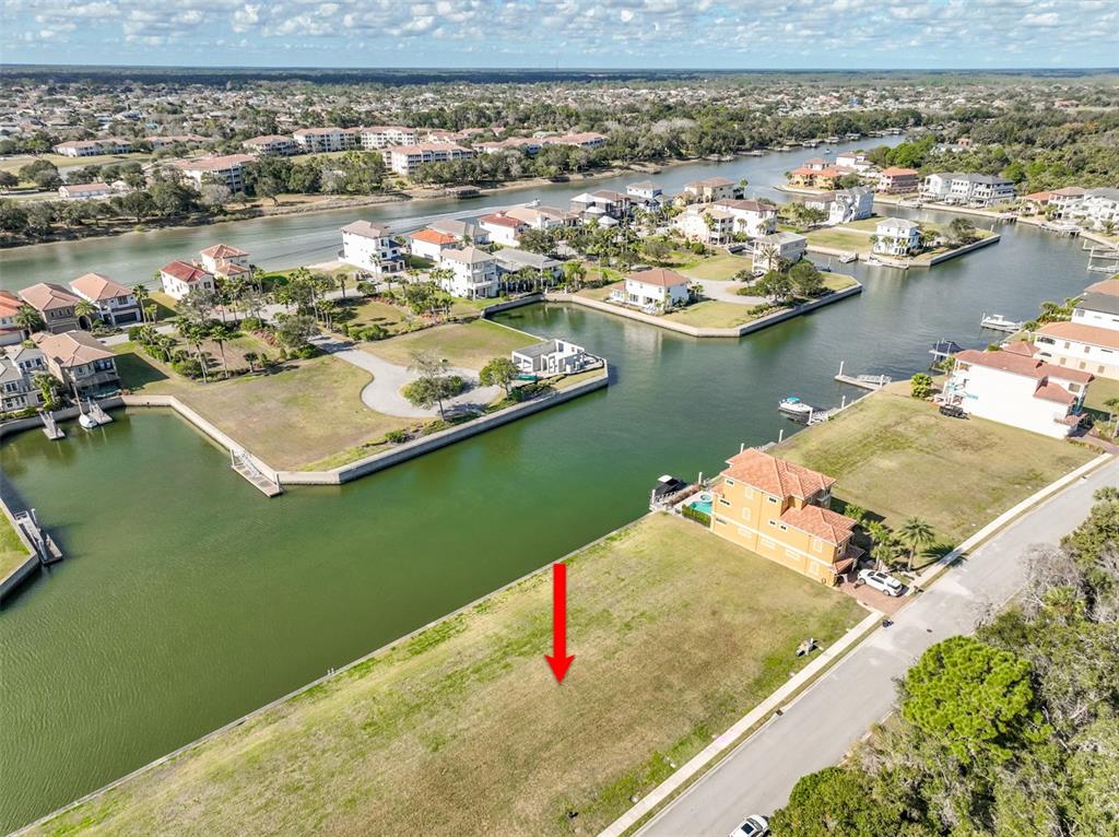 An aerial view shows a vacant waterfront lot next to a house with a pool — 268 HARBOR VILLAGE POINT N, PALM COAST, FL