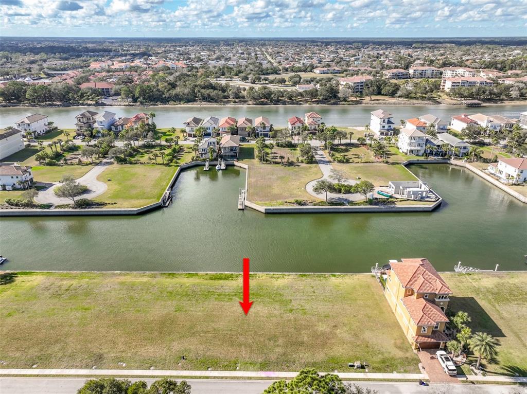 An aerial view shows a vacant waterfront lot with a red arrow pointing downward — 268 HARBOR VILLAGE POINT N, PALM COAST, FL