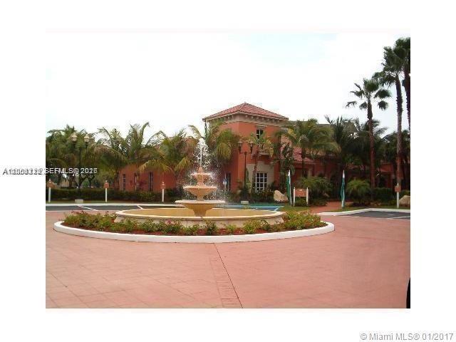 A tiered fountain sits in the center of a circular driveway in front of a building — 8363 Lake Dr # 102, Doral FL 33166, DORAL, FL