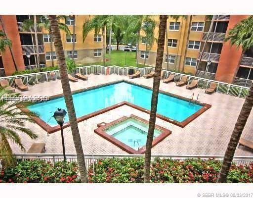 An L-shaped swimming pool and a square hot tub are surrounded by a paved deck — 8363 Lake Dr # 102, Doral FL 33166, DORAL, FL
