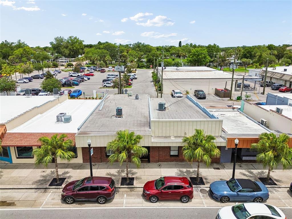 An aerial view shows a row of commercial storefronts with palm trees and parked cars — 5701 MAIN STREET, NEW PORT RICHEY, FL