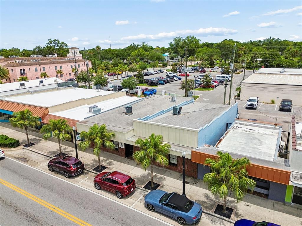 An aerial view shows a row of commercial buildings with palm trees and parked cars — 5701 MAIN STREET, NEW PORT RICHEY, FL