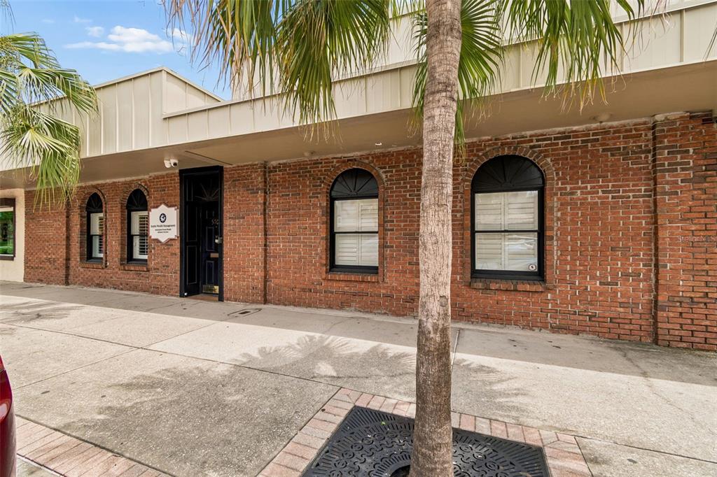A brick commercial building exterior features arched windows with shutters and a central dark door — 5701 MAIN STREET, NEW PORT RICHEY, FL