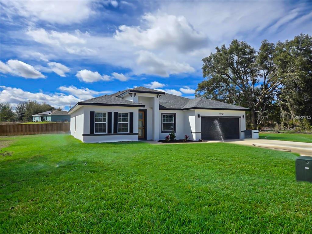 A single-story house with white stucco walls, a dark roof, and a two-car garage — 15092 SW 52ND COURT, OCALA, FL