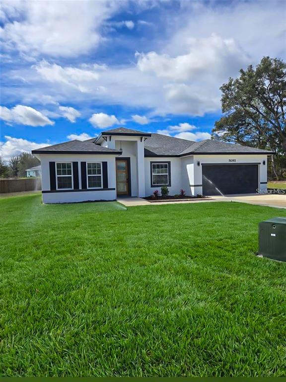 A single-story house with a white exterior, dark roof, and a two-car garage — 15092 SW 52ND COURT, OCALA, FL