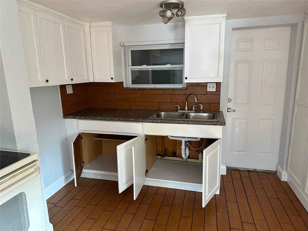 A kitchen features white cabinets, a brown tiled backsplash, a double sink, and tiled flooring — 3718 19TH AVENUE S, ST PETERSBURG, FL