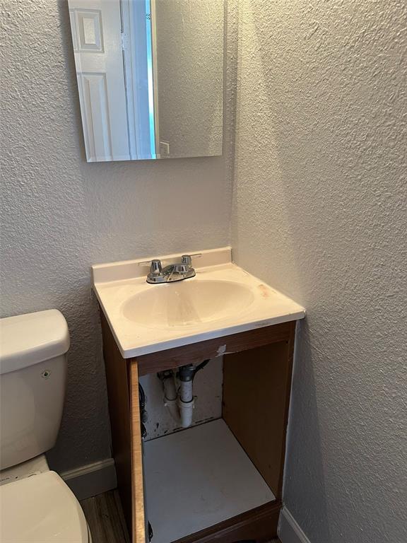 A bathroom vanity with a white sink and open cabinet sits next to a toilet — 3718 19TH AVENUE S, ST PETERSBURG, FL
