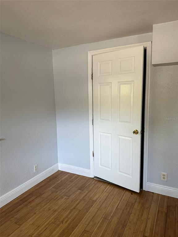 A room with light blue walls, wood flooring, and a white six-panel door — 3718 19TH AVENUE S, ST PETERSBURG, FL