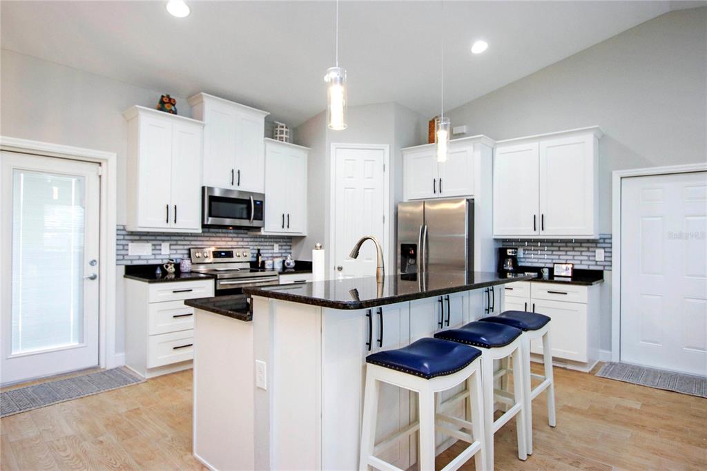 A kitchen features white cabinets, dark granite countertops, stainless steel appliances, and a breakfast bar — 4446 BAYANO STREET, NORTH PORT, FL