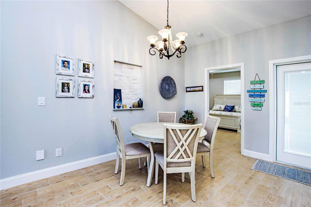 A dining area features a round table, four chairs, a chandelier, and light-colored wood flooring — 4446 BAYANO STREET, NORTH PORT, FL