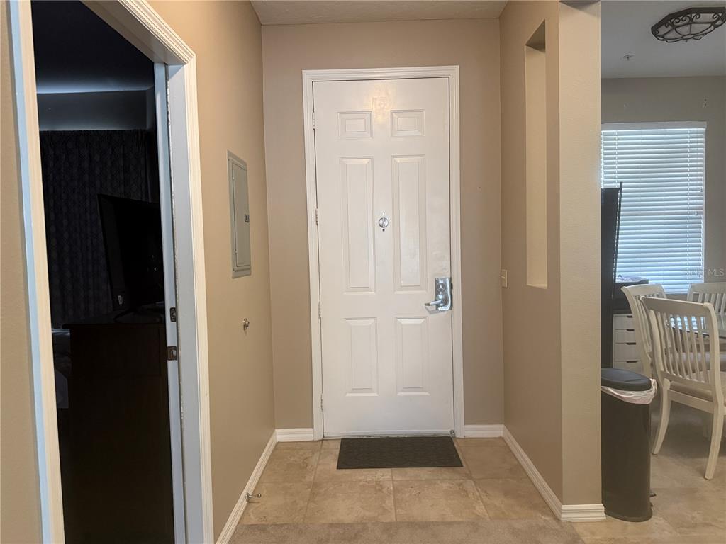 An entryway features a white front door, tile flooring, and a doorway leading to a room — 3506 54TH DRIVE W UNIT 203, BRADENTON, FL