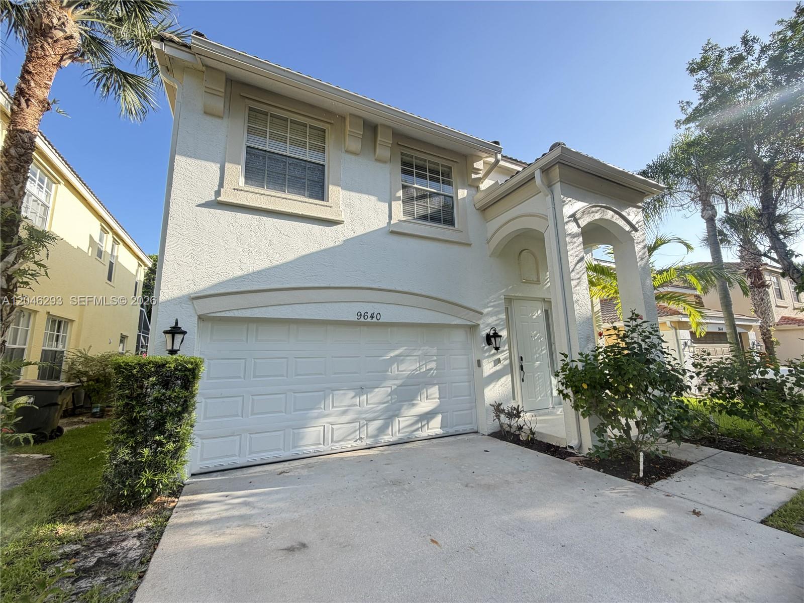 A two-story white stucco house features a two-car garage and a covered front entryway — 9640 Wyeth Ct, Wellington FL 33414, WELLINGTON, FL