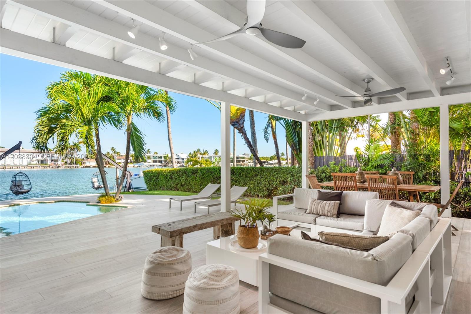 A covered outdoor patio features a seating area, dining table, and pool overlooking a canal — 365 N Shore Dr, Miami Beach FL 33141, MIAMI BEACH, FL