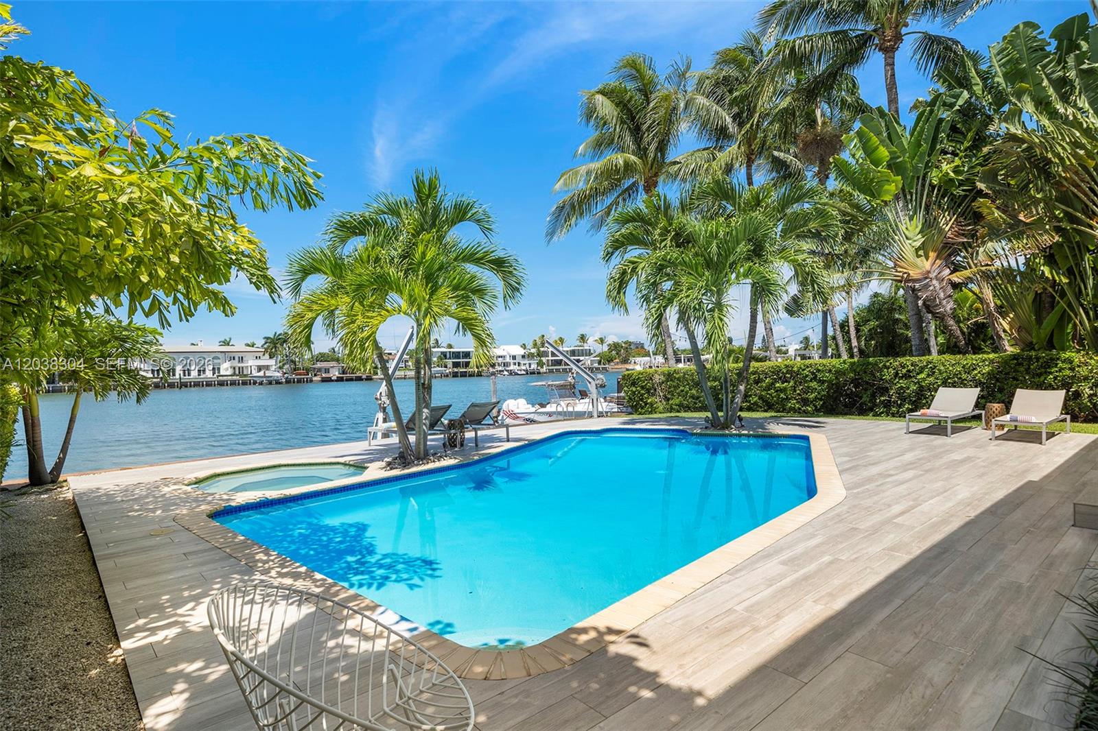 A swimming pool and patio area overlook a canal with palm trees and lounge chairs — 365 N Shore Dr, Miami Beach FL 33141, MIAMI BEACH, FL