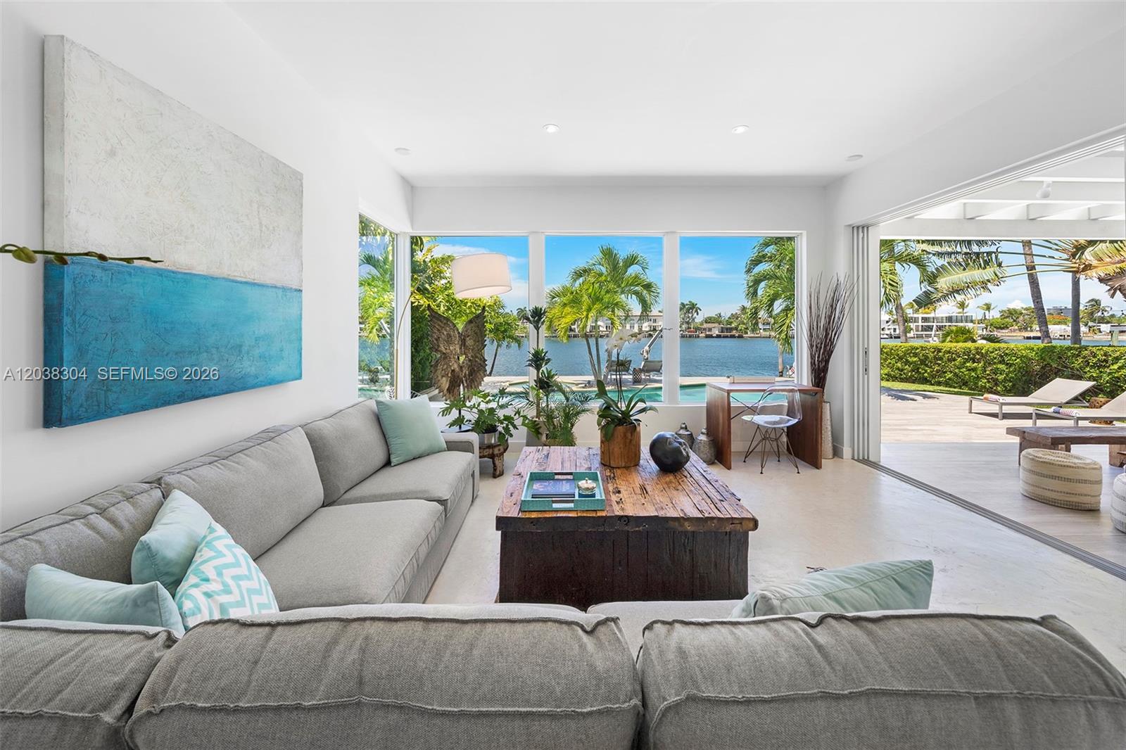 A living room features a grey sectional sofa, a rustic coffee table, and large windows — 365 N Shore Dr, Miami Beach FL 33141, MIAMI BEACH, FL