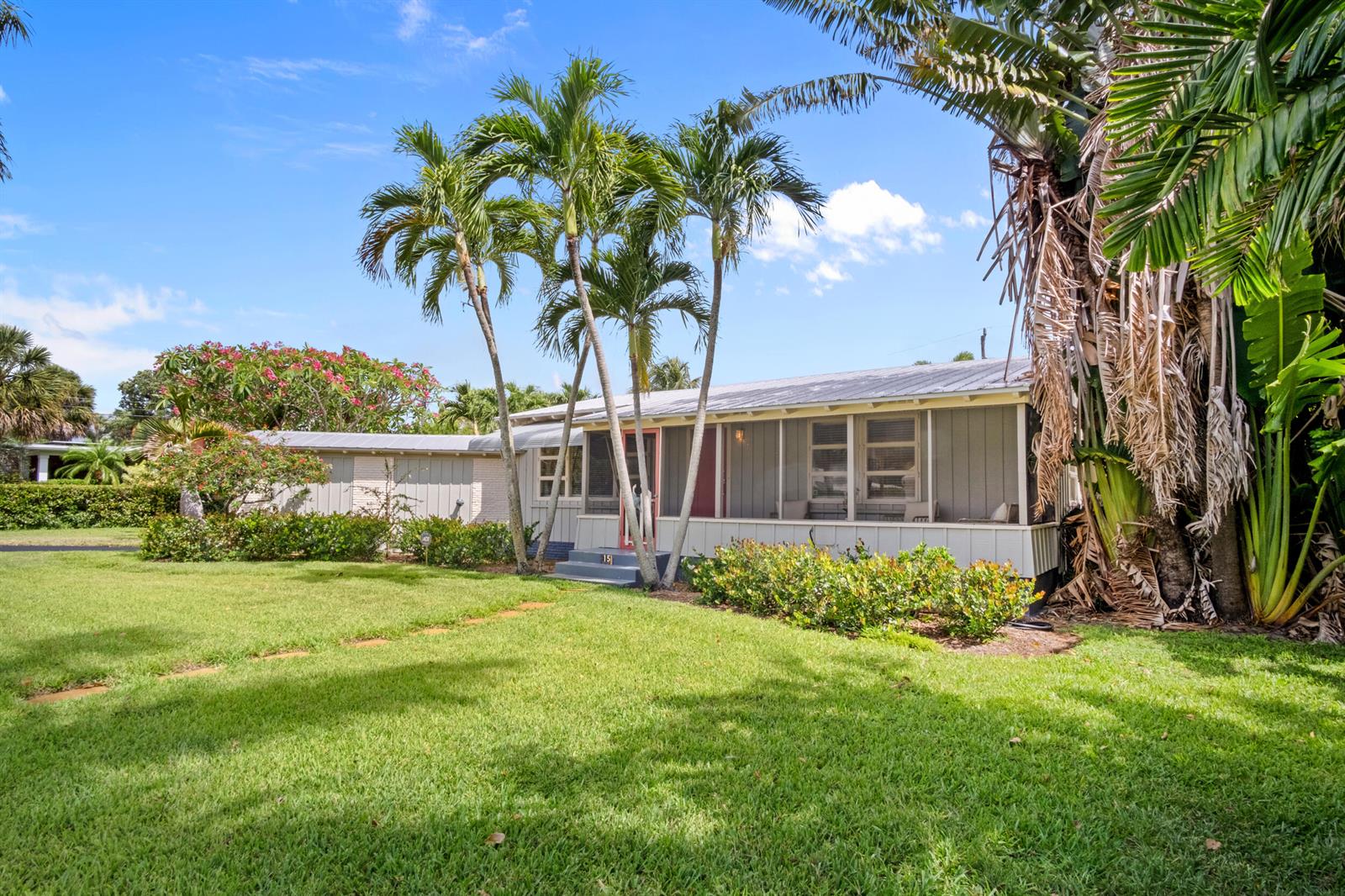 A single-story house with a screened porch and palm trees sits on a grassy lawn — 15 N Swinton Circle, Delray Beach FL 33444, DELRAY BEACH, FL