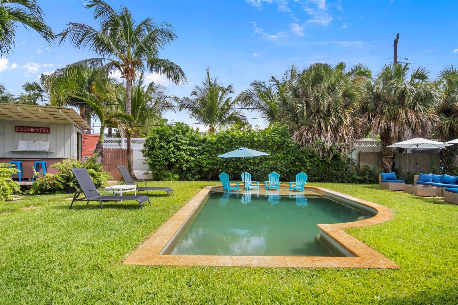 A backyard features a swimming pool, lounge chairs, a patio umbrella, and a small structure — 15 N Swinton Circle, Delray Beach FL 33444, DELRAY BEACH, FL