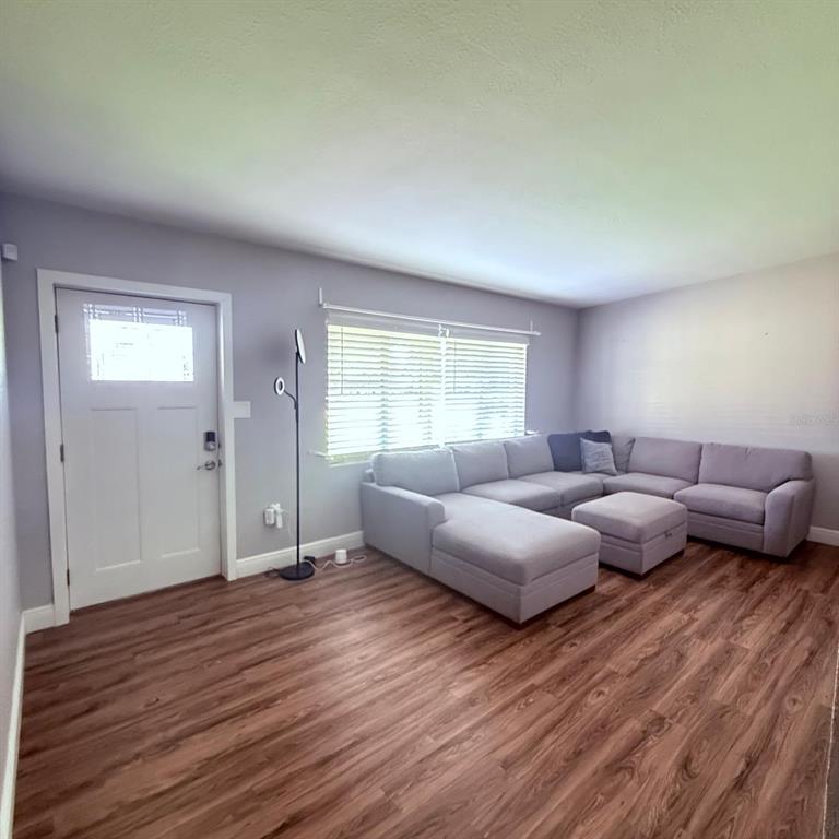 A living room features light gray walls, wood-look flooring, a sectional sofa, and a front door — 2940 LAKE MARGARET DRIVE, ORLANDO, FL