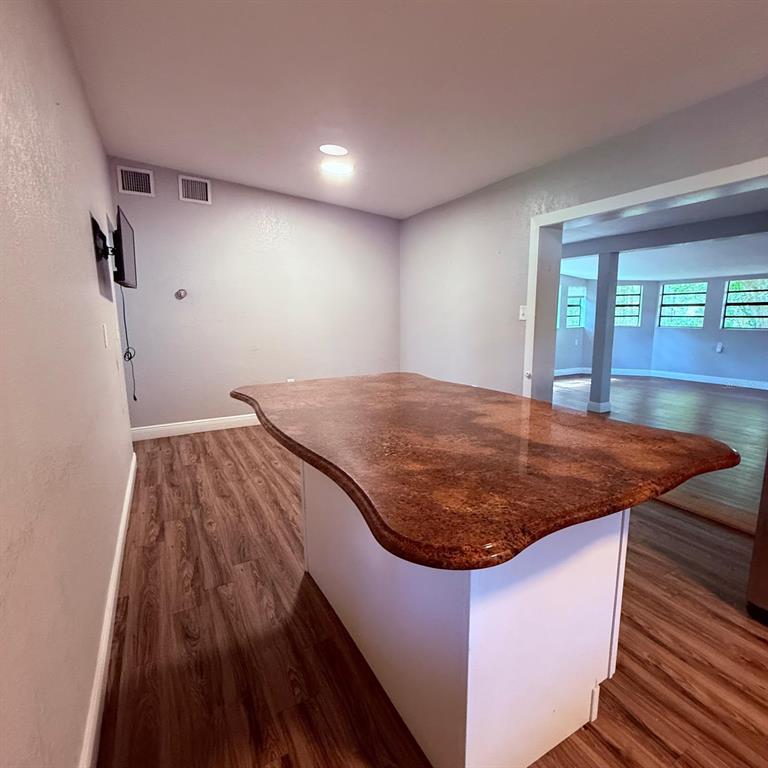 A kitchen island with a reddish-brown countertop sits in a room with wood-look flooring — 2940 LAKE MARGARET DRIVE, ORLANDO, FL