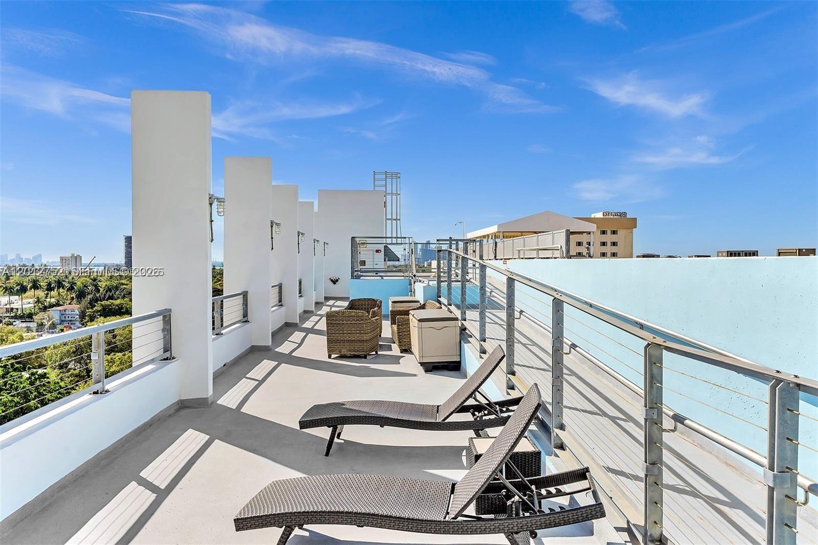 A rooftop terrace features lounge chairs, wicker seating, and metal railings under a blue sky — 8101 Biscayne Blvd # 410, Miami FL 33138, MIAMI, FL