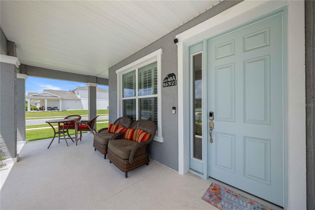 A covered front porch features wicker chairs, a small table, and a light blue door — 7539 SW 64TH STREET ROAD, OCALA, FL