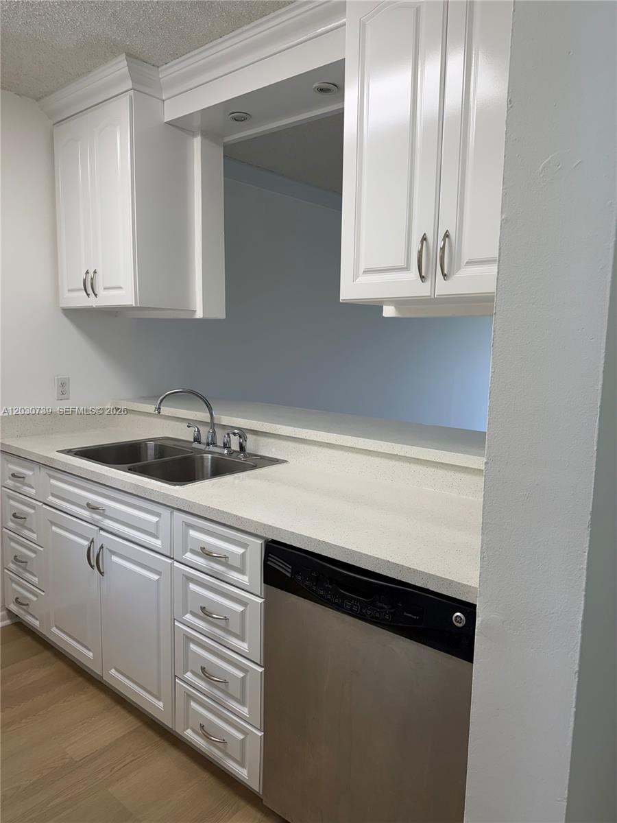 A kitchen features white cabinets, a stainless steel dishwasher, and a double-basin sink — 8560 N Sherman Cir # 404, Miramar FL 33025, MIRAMAR, FL