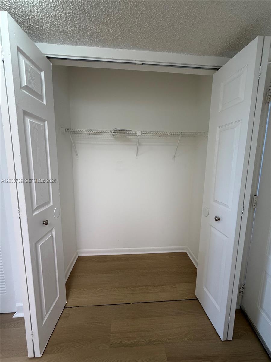 An open closet features white double doors, a wire shelf, and light wood-look flooring — 8560 N Sherman Cir # 404, Miramar FL 33025, MIRAMAR, FL