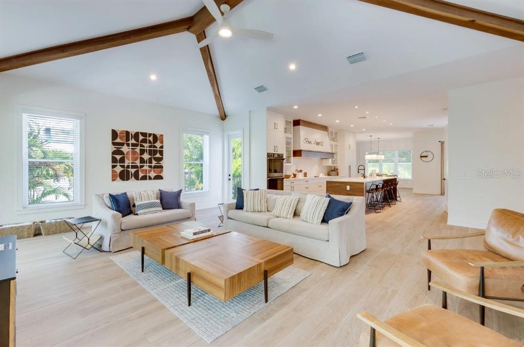 A living room with vaulted ceilings, exposed beams, and an open kitchen in the background — 9407 GULF DR, ANNA MARIA, FL
