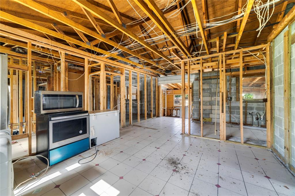 An unfinished room with exposed wood framing, concrete block walls, and a freestanding stove — 6427 SUNSHINE STREET, ORLANDO, FL