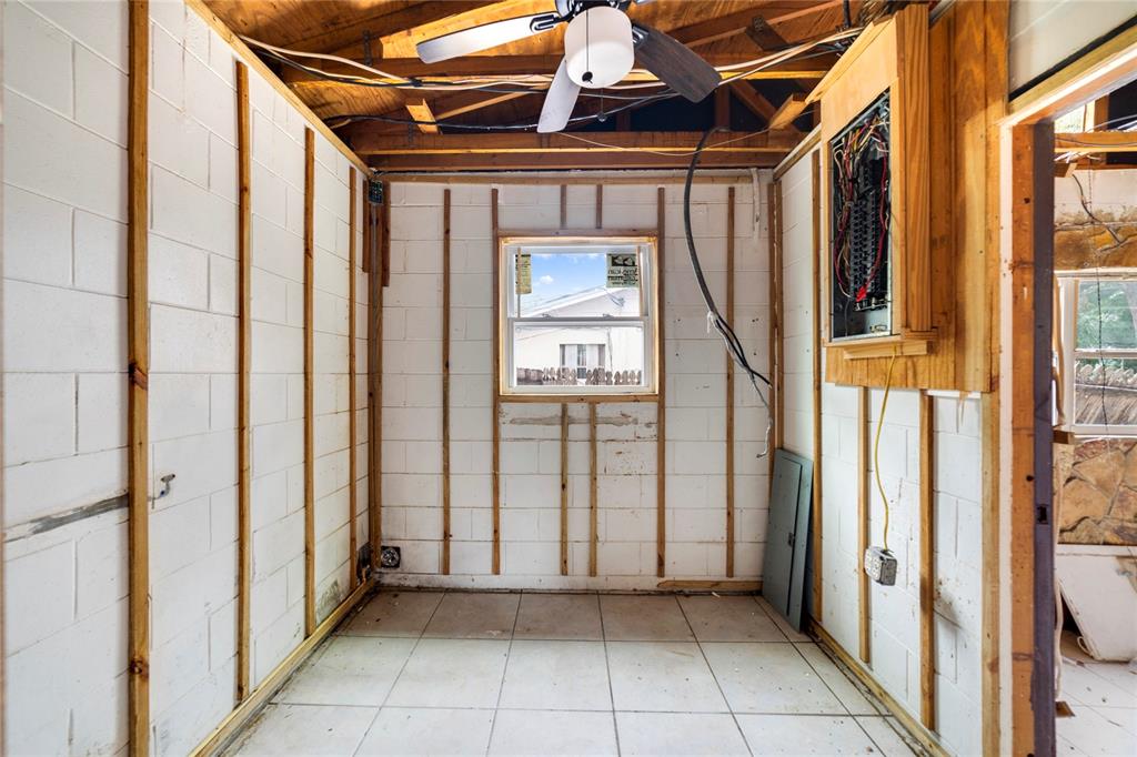 An unfinished room features exposed concrete block walls, wood furring strips, tiled flooring, and an electrical panel — 6427 SUNSHINE STREET, ORLANDO, FL
