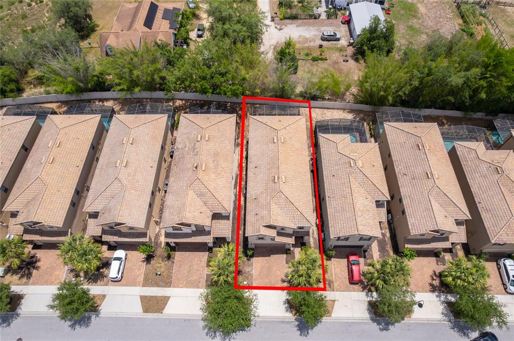An aerial view shows a row of townhomes with tiled roofs and a red outline highlighting one unit — 1881 NICE COURT, KISSIMMEE, FL