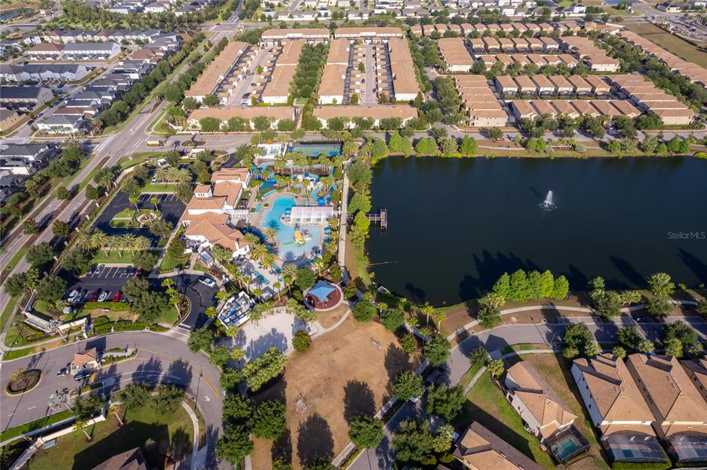 Aerial view of a residential community featuring a large swimming pool, clubhouse, and lake — 1881 NICE COURT, KISSIMMEE, FL