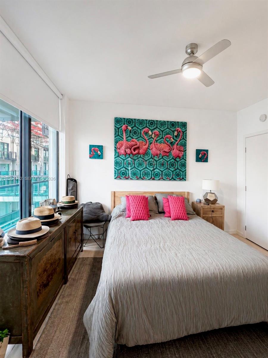 A bedroom features a bed with pink pillows, flamingo wall art, and a ceiling fan — 6000 Collins Ave # 515, Miami Beach FL 33140, MIAMI BEACH, FL