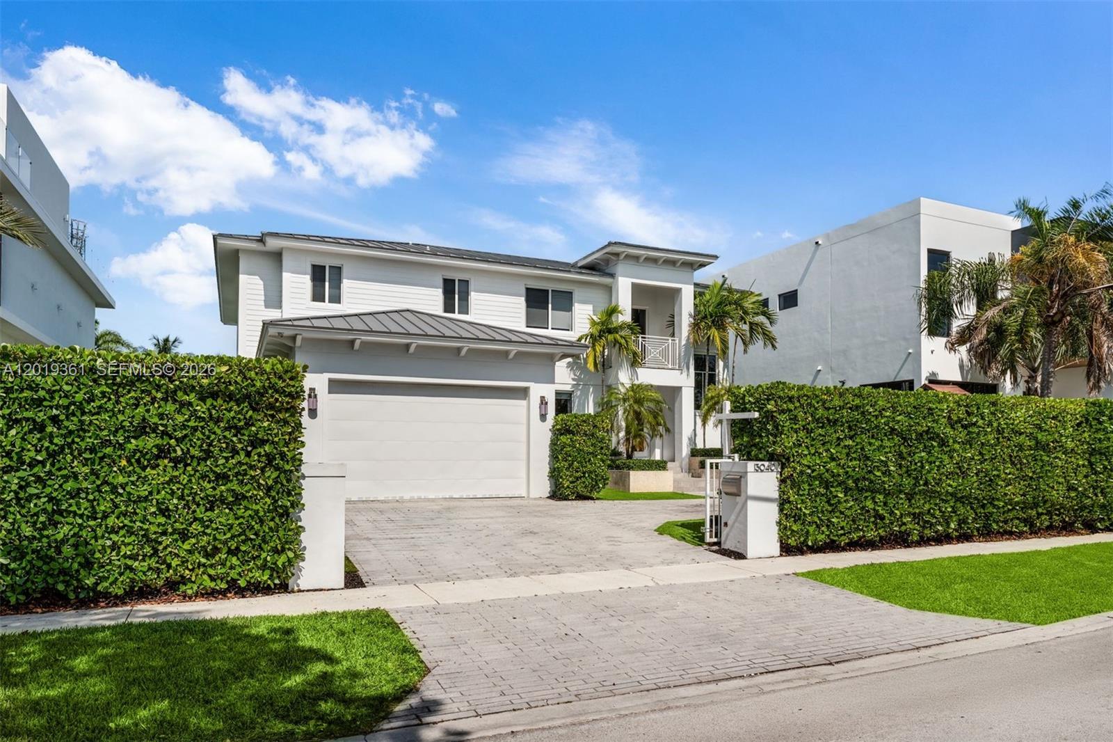 A two-story white house with a paved driveway and a tall green privacy hedge — 13040 N Bayshore Dr, North Miami FL 33181, NORTH MIAMI, FL