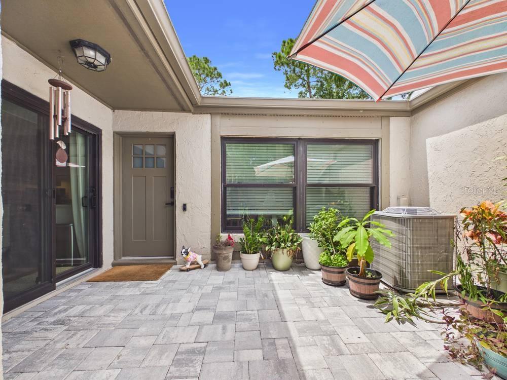 A paved patio features a sliding glass door, a side door, and several potted plants — 407 MEADOWOOD BOULEVARD, FERN PARK, FL