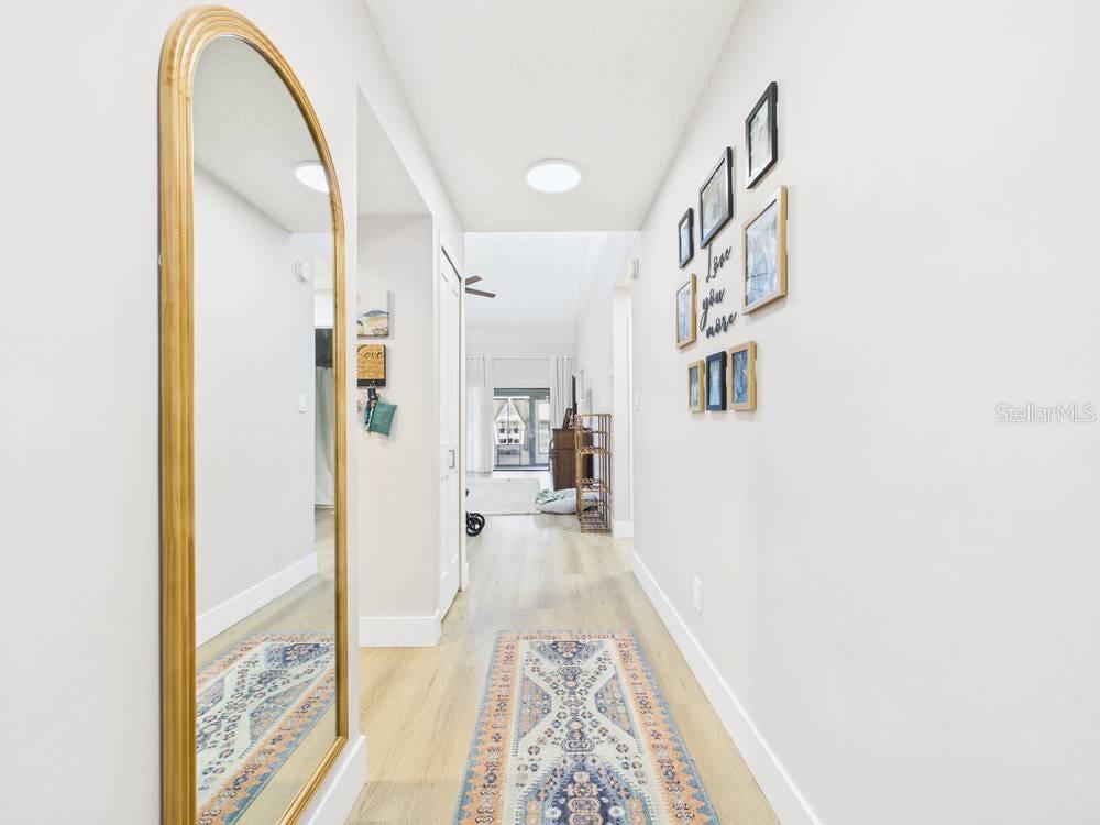 A hallway features a large arched mirror, a patterned runner rug, and a gallery wall — 407 MEADOWOOD BOULEVARD, FERN PARK, FL