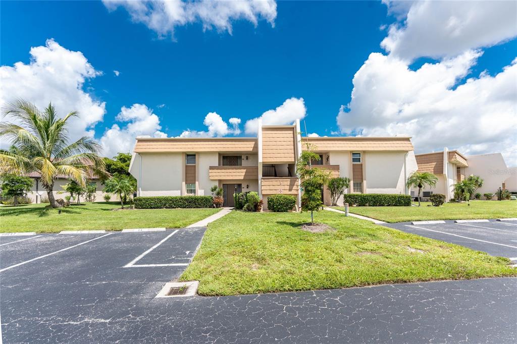 A two-story tan apartment building features a central entryway and a paved parking lot — 1080 BAL HARBOR BOULEVARD UNIT 1A, PUNTA GORDA, FL
