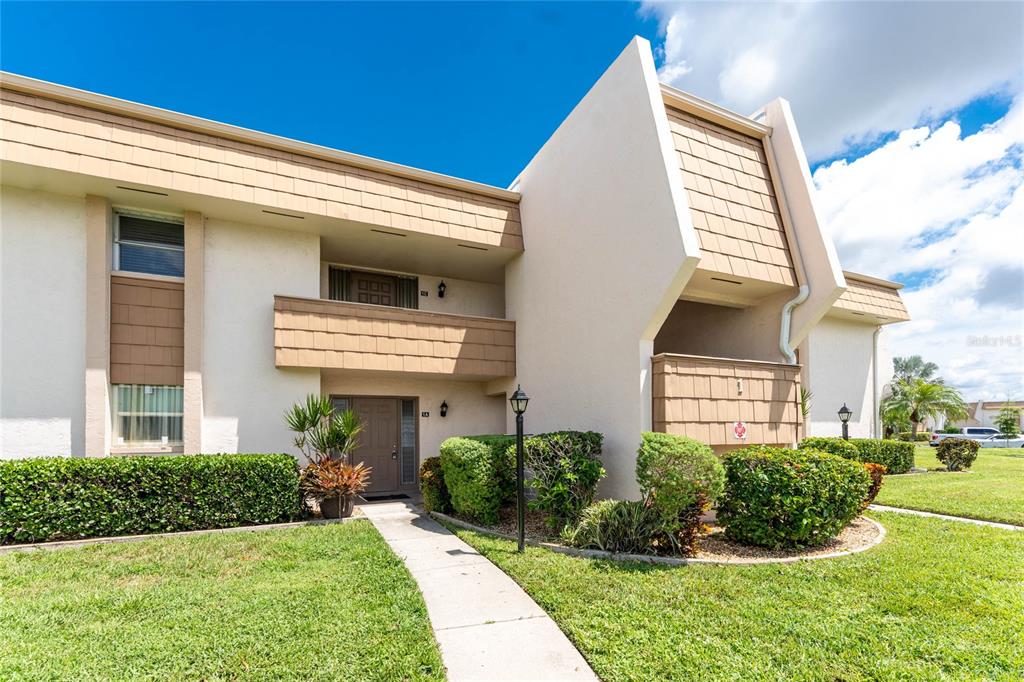 A two-story residential building with tan stucco walls, brown shingle accents, and a concrete walkway — 1080 BAL HARBOR BOULEVARD UNIT 1A, PUNTA GORDA, FL