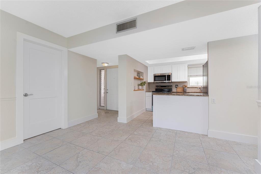 A kitchen with white cabinets and a breakfast bar opens into a tiled dining area — 1080 BAL HARBOR BOULEVARD UNIT 1A, PUNTA GORDA, FL
