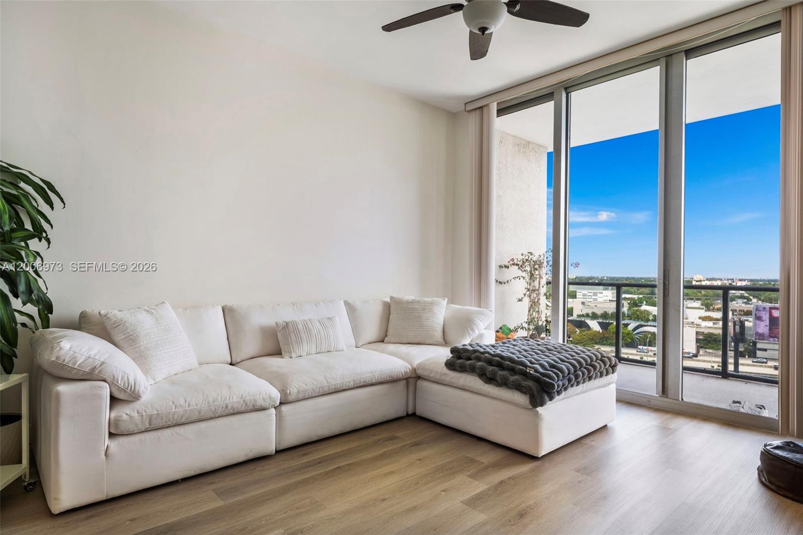 A living room features a white sectional sofa, light wood flooring, and floor-to-ceiling windows — 3470 E Coast Ave # H1203, Miami FL 33137, MIAMI, FL