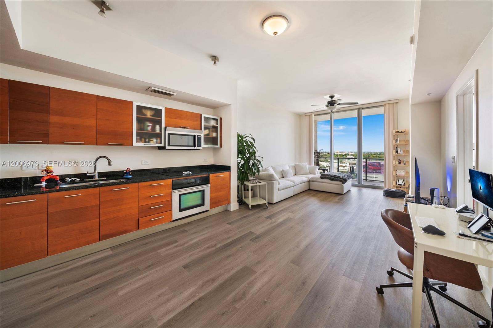 A modern studio apartment features a kitchen with wood cabinets and an adjacent living area — 3470 E Coast Ave # H1203, Miami FL 33137, MIAMI, FL