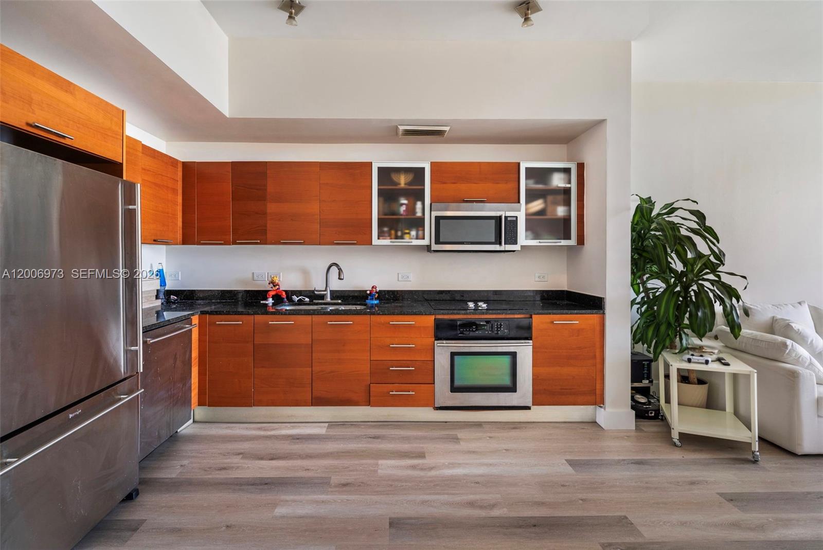 A kitchen features wood cabinets, stainless steel appliances, and dark countertops over wood-look flooring — 3470 E Coast Ave # H1203, Miami FL 33137, MIAMI, FL