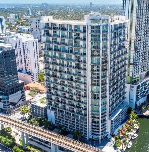 An aerial view shows a tall, modern residential high-rise building next to an elevated train track — 690 SW 1st Ct # 1227, Miami FL 33130, MIAMI, FL