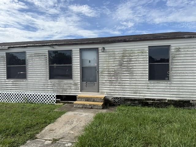 The exterior of a weathered, single-story mobile home features white siding and a front entrance — 36118 ZINNIA AVENUE, ZEPHYRHILLS, FL