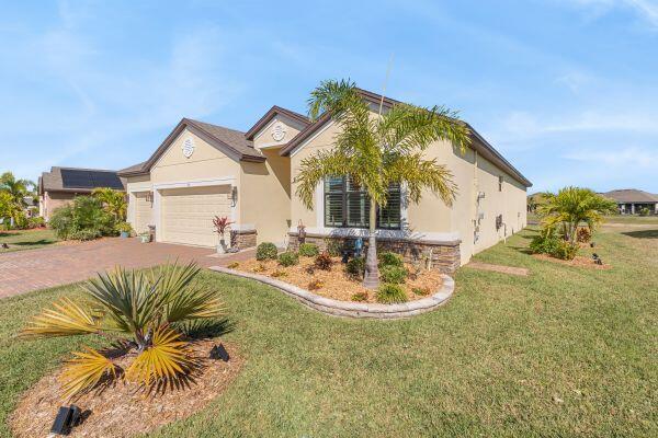 A beige single-story house with a two-car garage and a landscaped front yard — 80 56th Court, Vero Beach FL 32968, VERO BEACH, FL