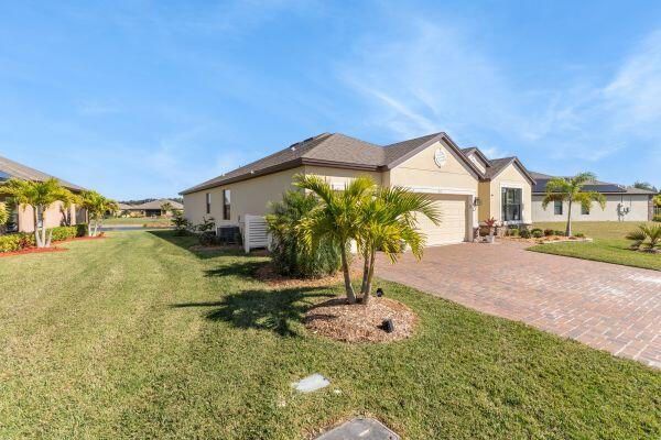 A single-story house with a brick driveway, palm trees, and a tan stucco exterior — 80 56th Court, Vero Beach FL 32968, VERO BEACH, FL
