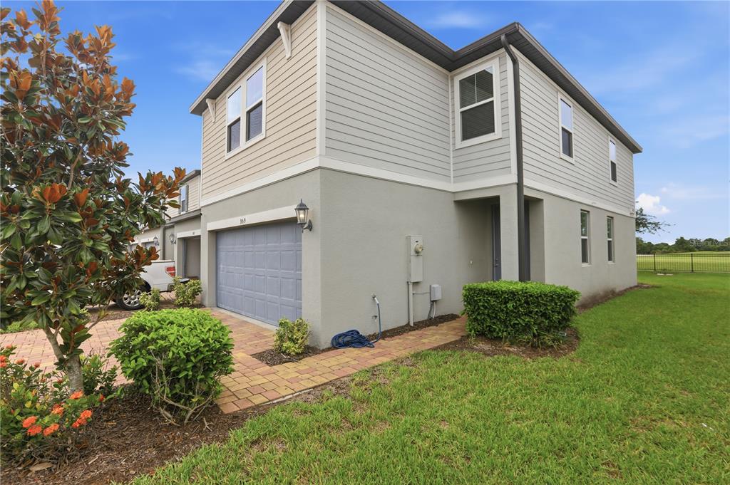 A two-story townhouse with a gray garage, beige siding, and a paver walkway — 959 ROBIN HOLLY STREET, OCOEE, FL