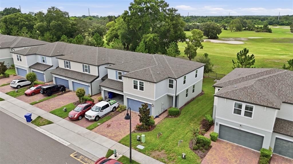 An aerial view shows a row of multi-story townhomes with attached garages and paved driveways — 959 ROBIN HOLLY STREET, OCOEE, FL