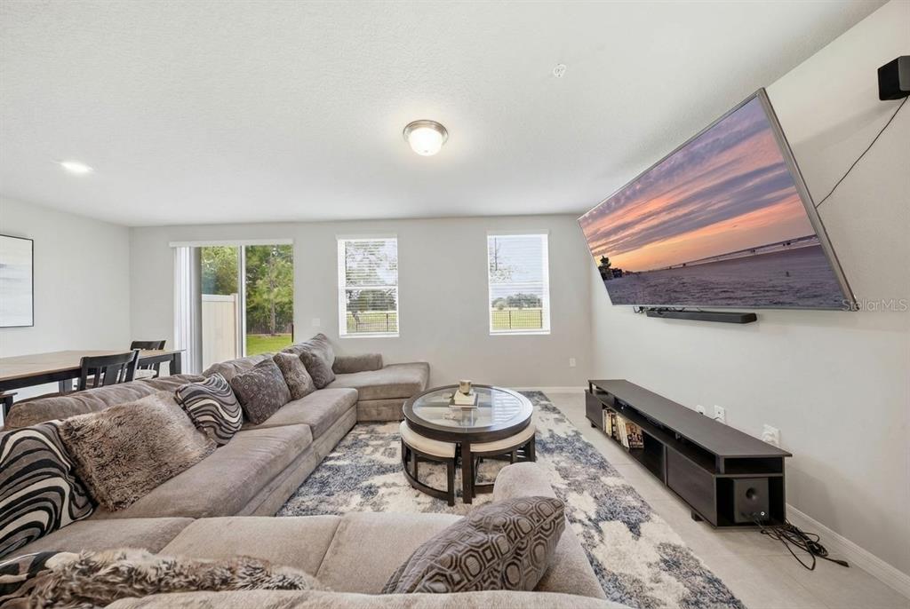 A living room with a large sectional sofa, a coffee table, and a wall-mounted television — 959 ROBIN HOLLY STREET, OCOEE, FL