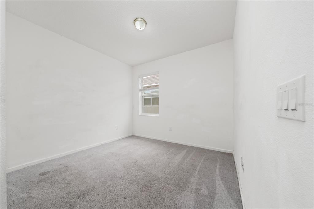 An empty bedroom features white walls, gray carpet, a single window, and a ceiling light — 417 SAPPHIRE DRIVE, DAVENPORT, FL